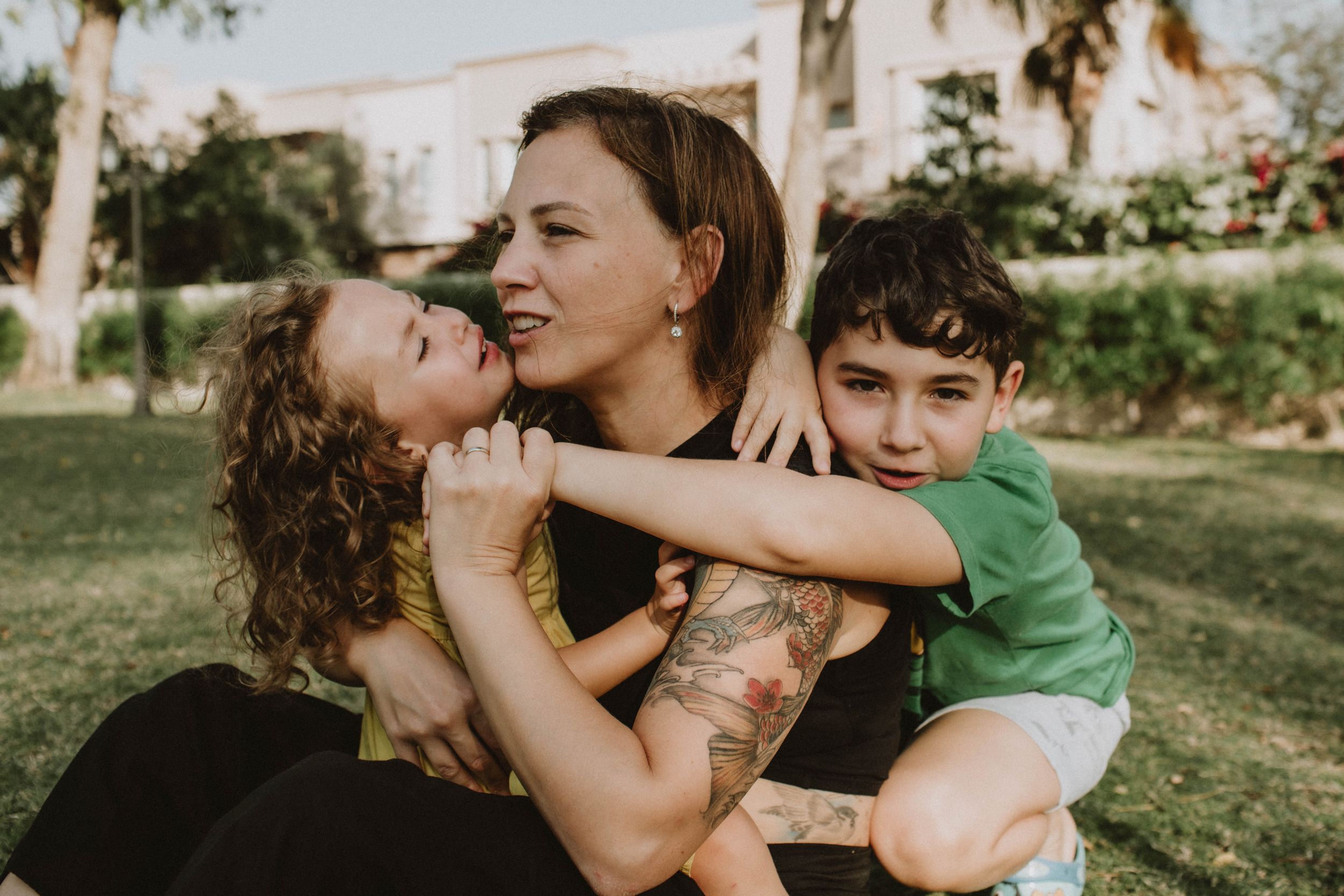 Heartfelt family session in Sydney & Northern Beaches, showing a mom embracing her two children in a park, celebrating love and connection.