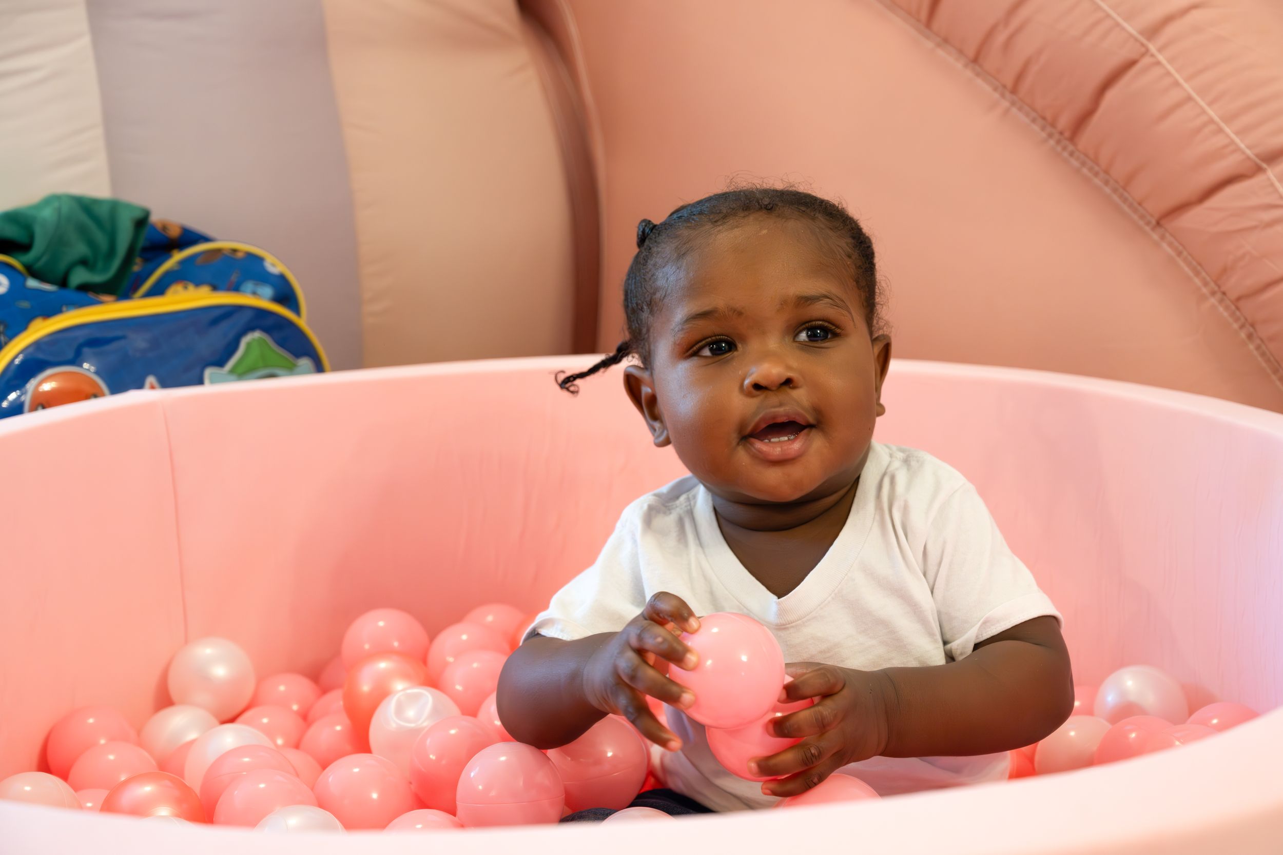 Young toddler enjoying playtime in pink inflatable ball pit.