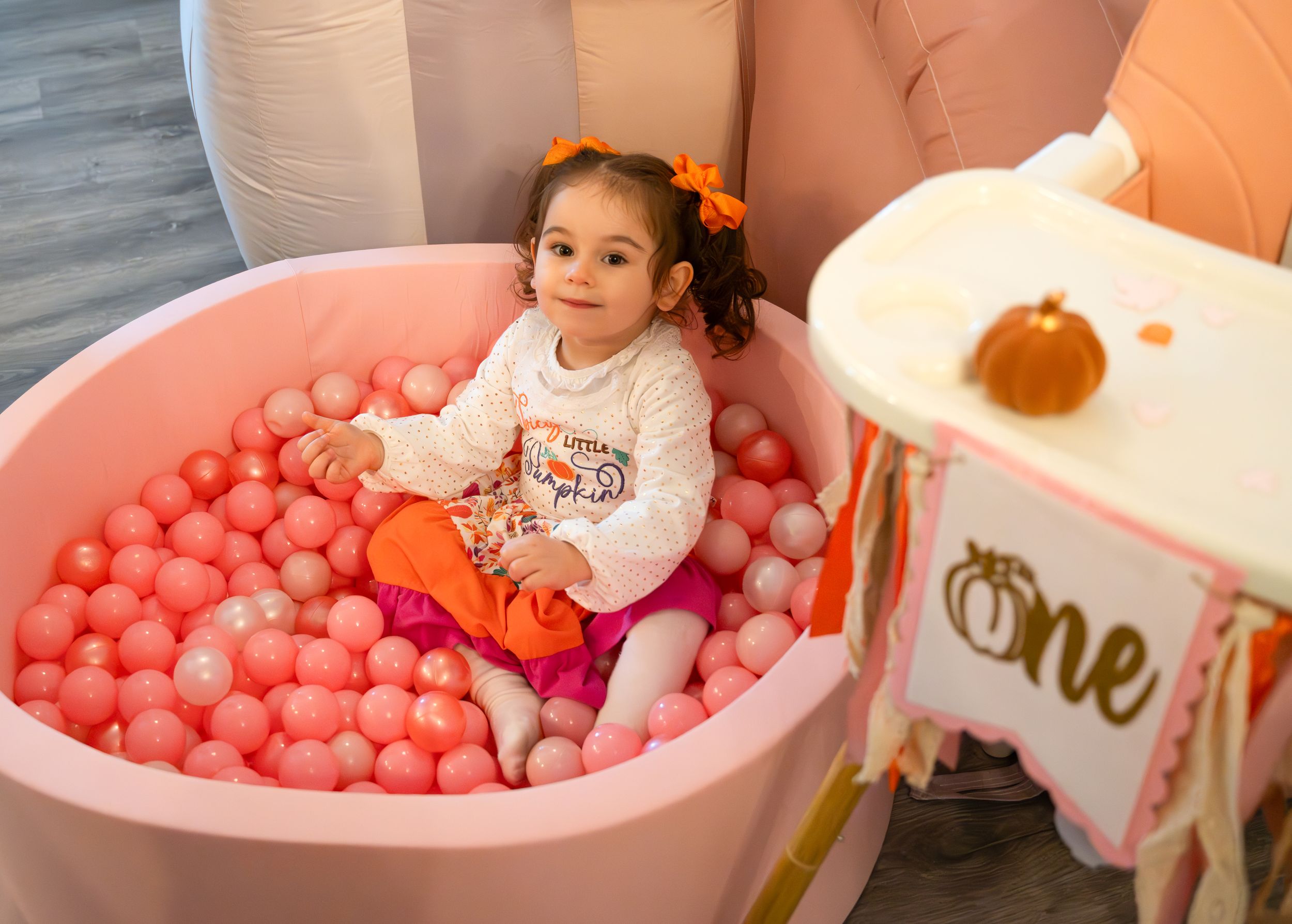 Children playing in pink ball pit during celebration with decorations.