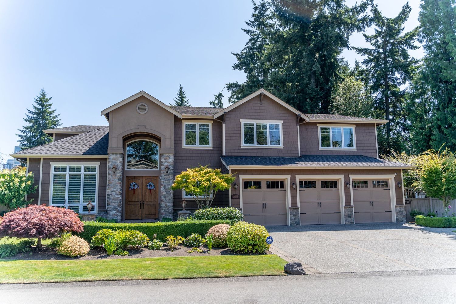 Luxury brown suburban house with three-car garage and manicured landscaping.