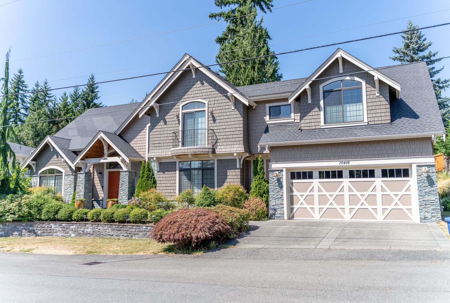 Large craftsman style home with stone accents and double garage featuring beautiful landscaping.