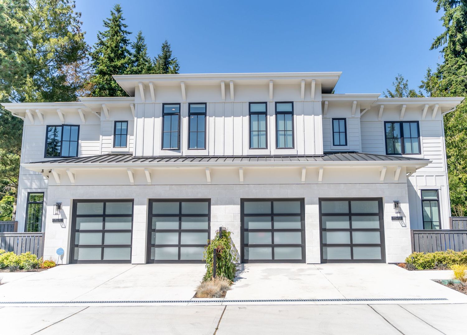 Modern white duplex with contemporary design featuring glass garage doors and clean lines.