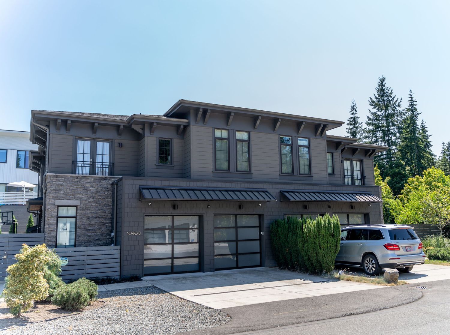 Contemporary dark gray two-story home with modern garage doors and architectural details.