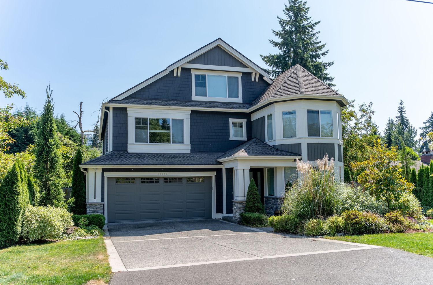 Navy blue craftsman style house with turret feature and attached garage on landscaped property.