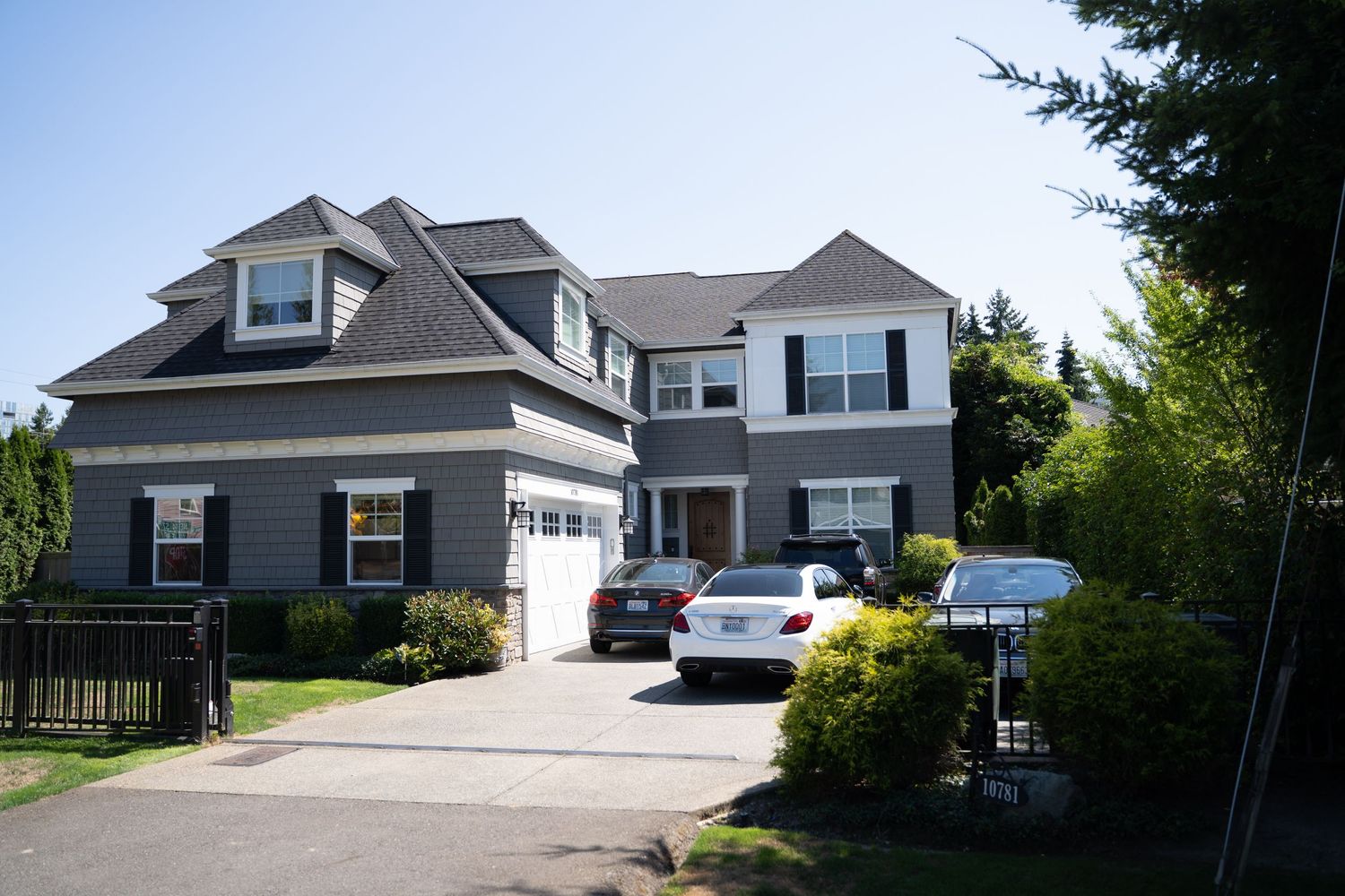 Two-story gray suburban home with white trim and attached garage on landscaped lot.
