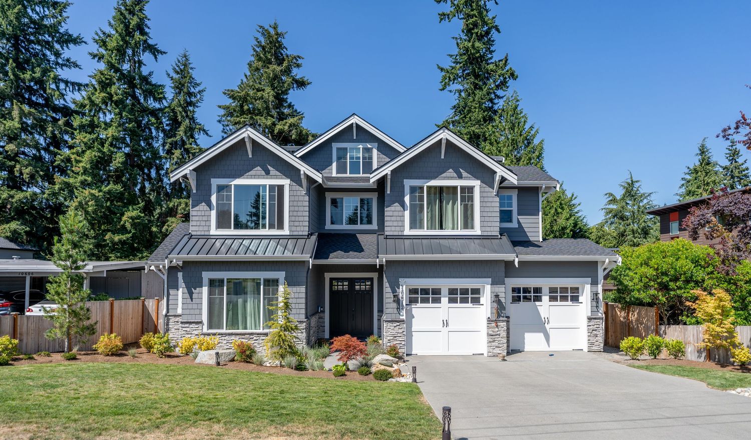 Coastal craftsman style home with white trim, double garage, and professionally landscaped front yard.