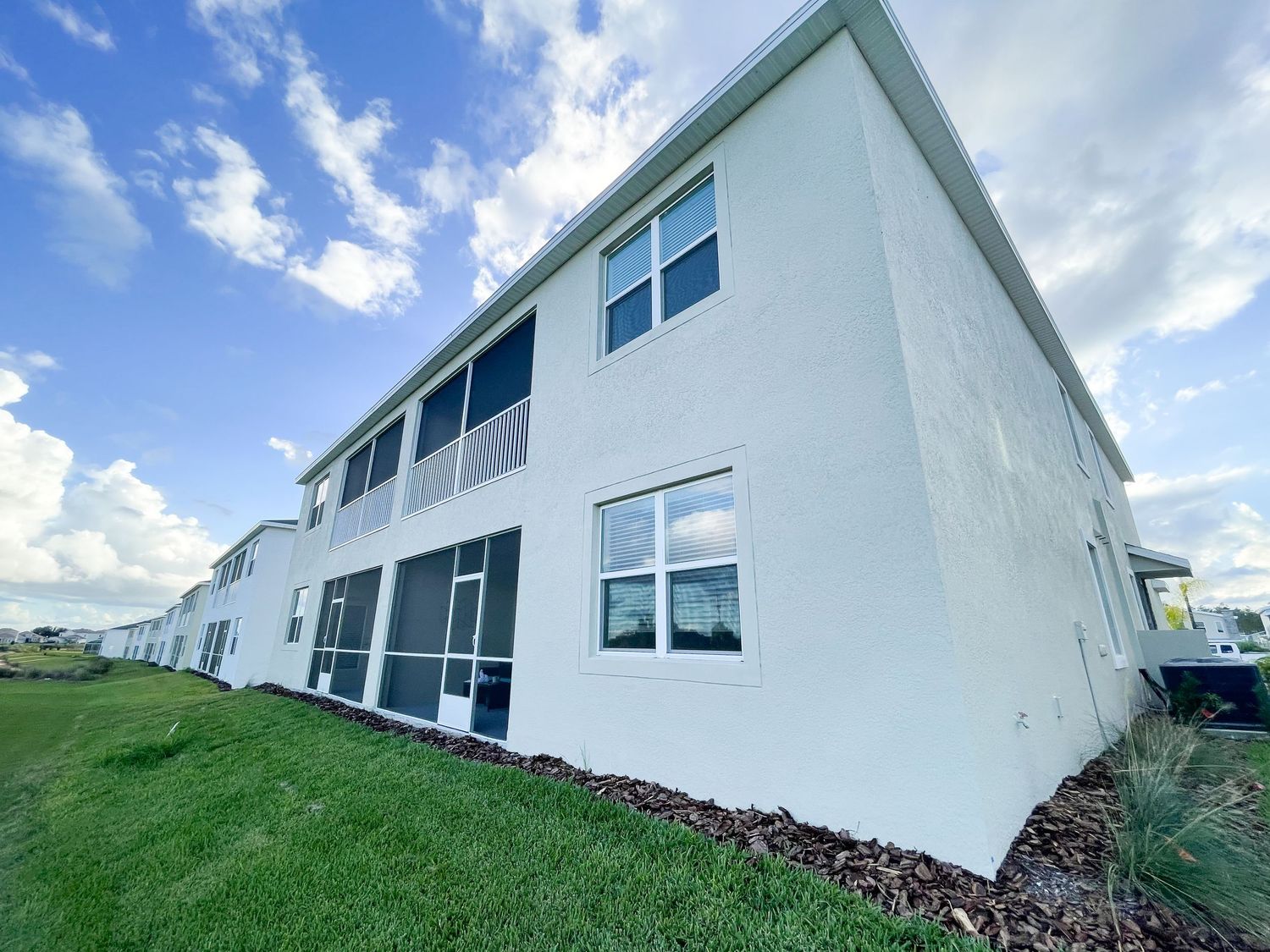 Modern white two-story building with large windows and black trim against blue sky.