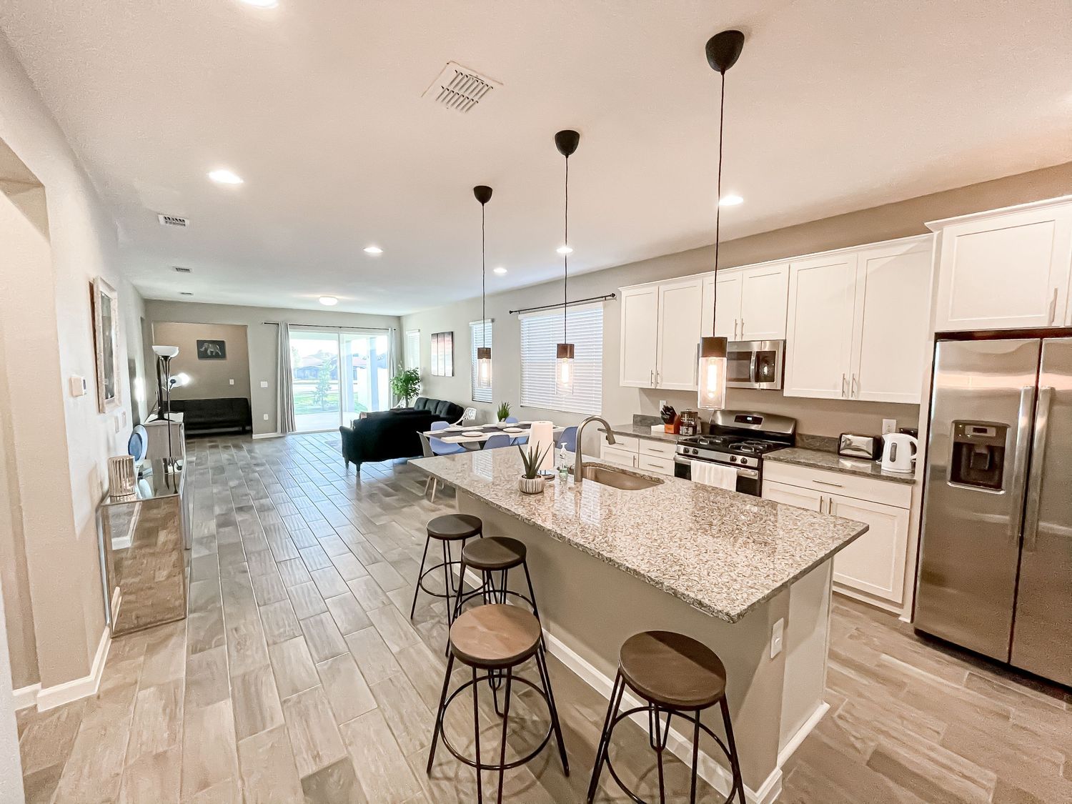 Modern open concept kitchen with granite island, stainless appliances and pendant lighting.