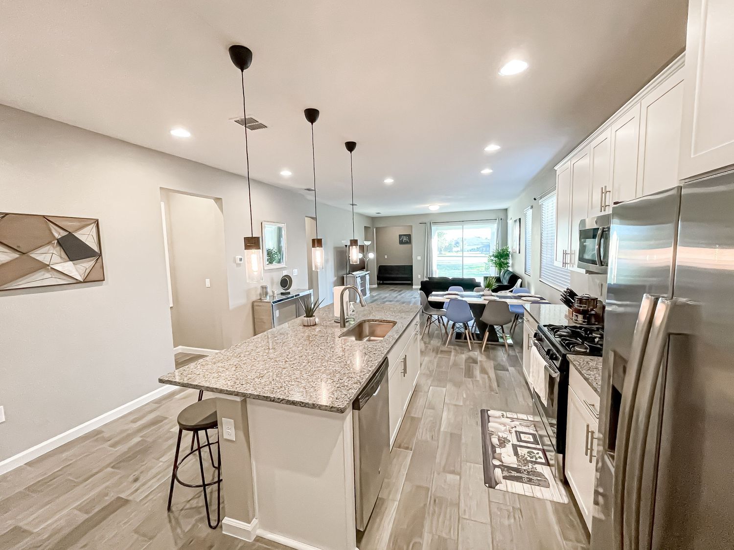 Contemporary kitchen and dining space with white cabinets, granite countertops and pendant lighting.
