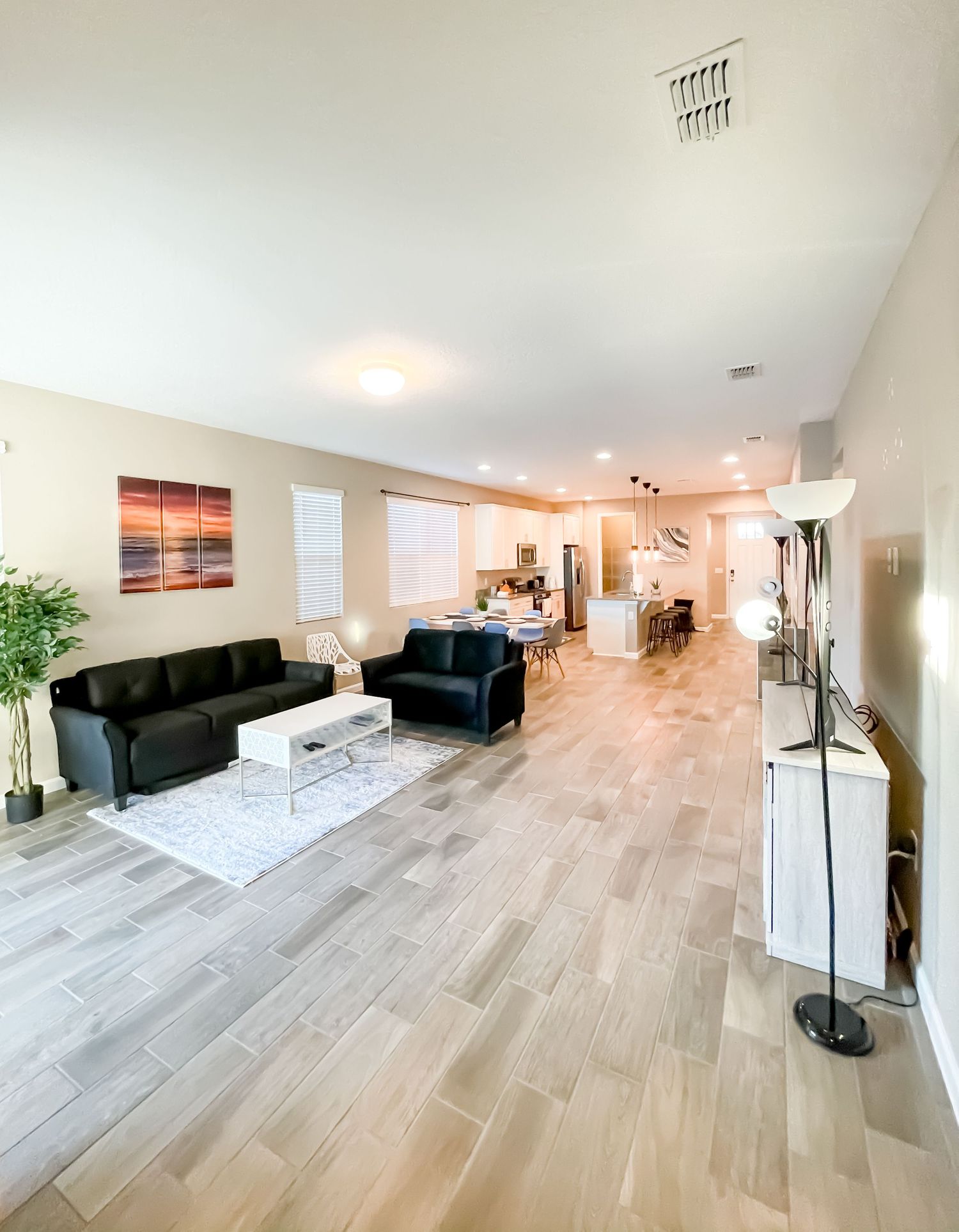 Spacious open floor plan living area with modern furniture and gray wood-look tile flooring.