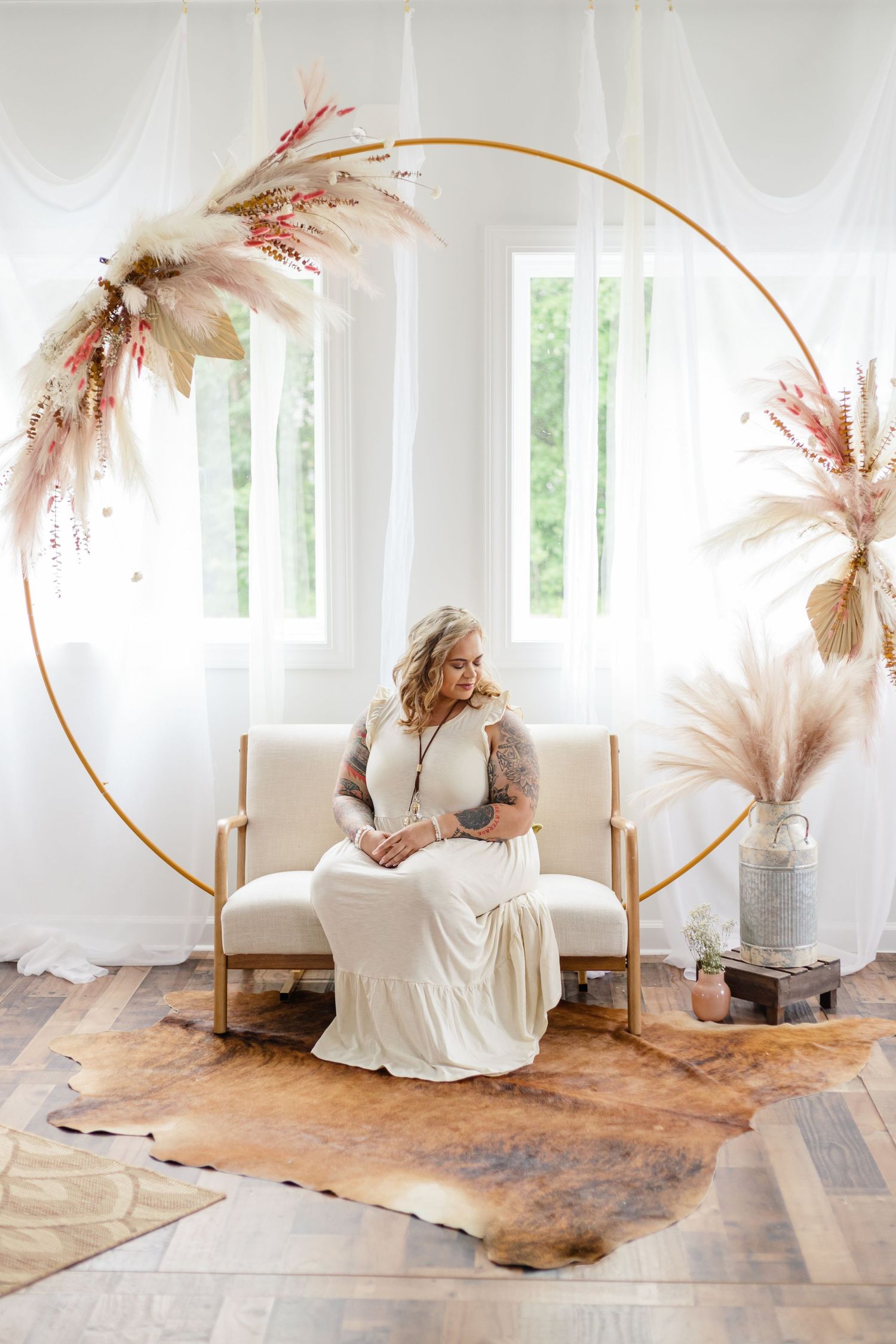 Elegant bridal portrait in white dress against circular gold arch adorned with pampas grass and natural light.