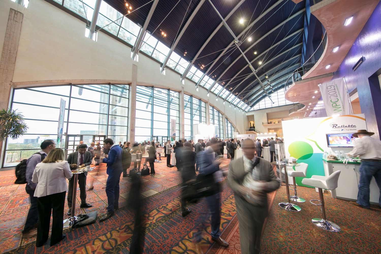 Wide angle view of convention center interior with curved ceiling and natural lighting.