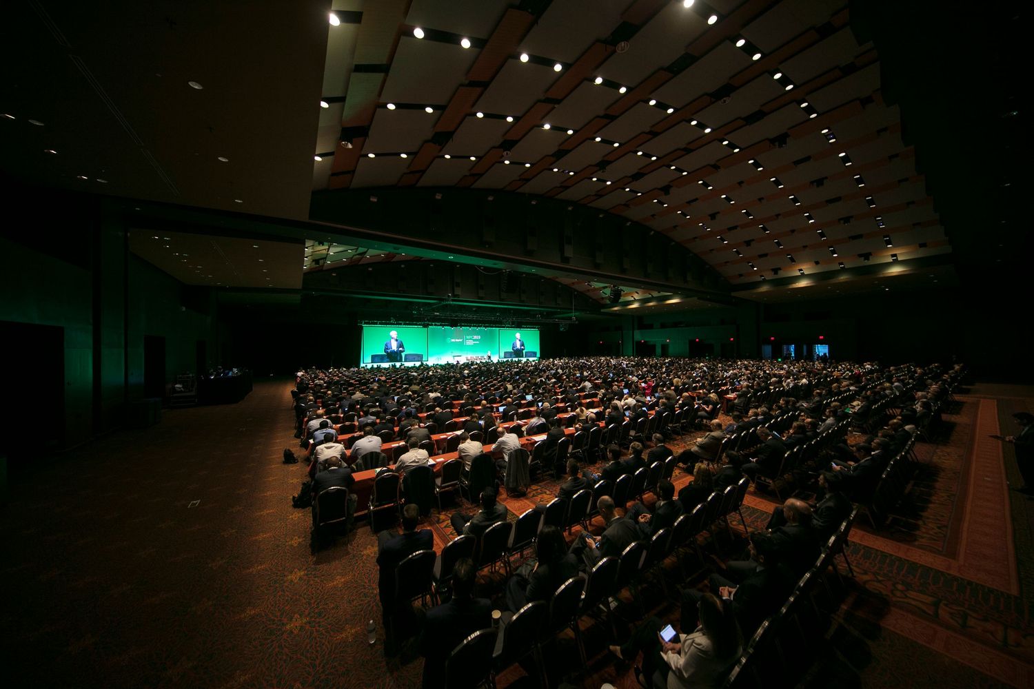 Dark auditorium filled with attendees and illuminated by stage lighting.