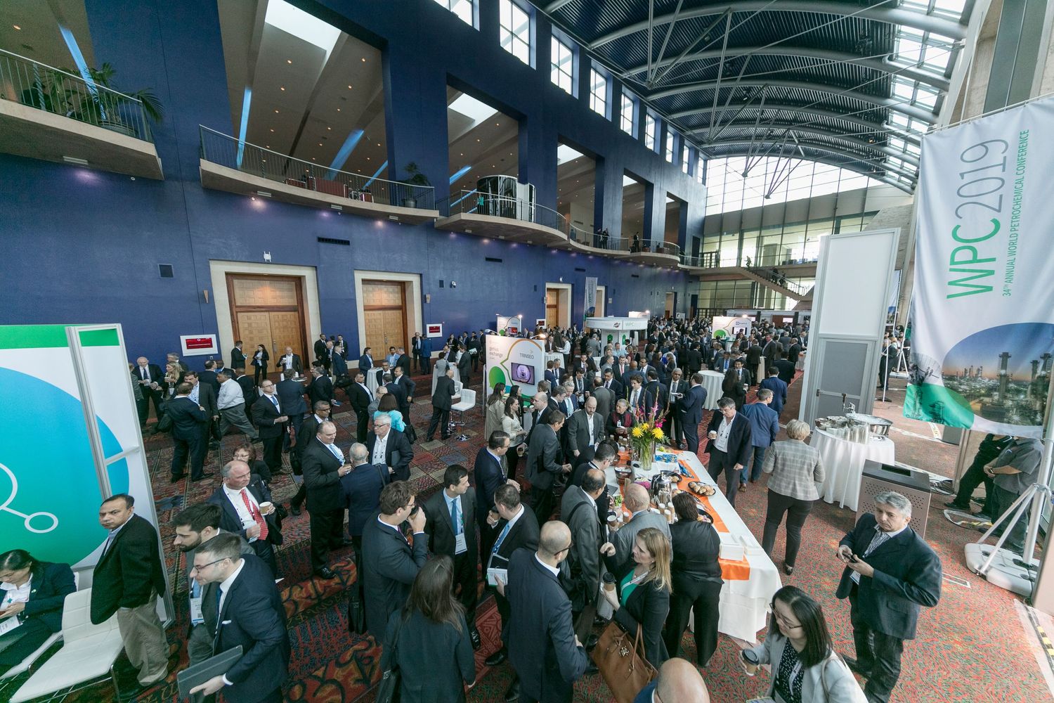 Large conference or trade show hall filled with attendees and exhibition booths displaying technology and products.