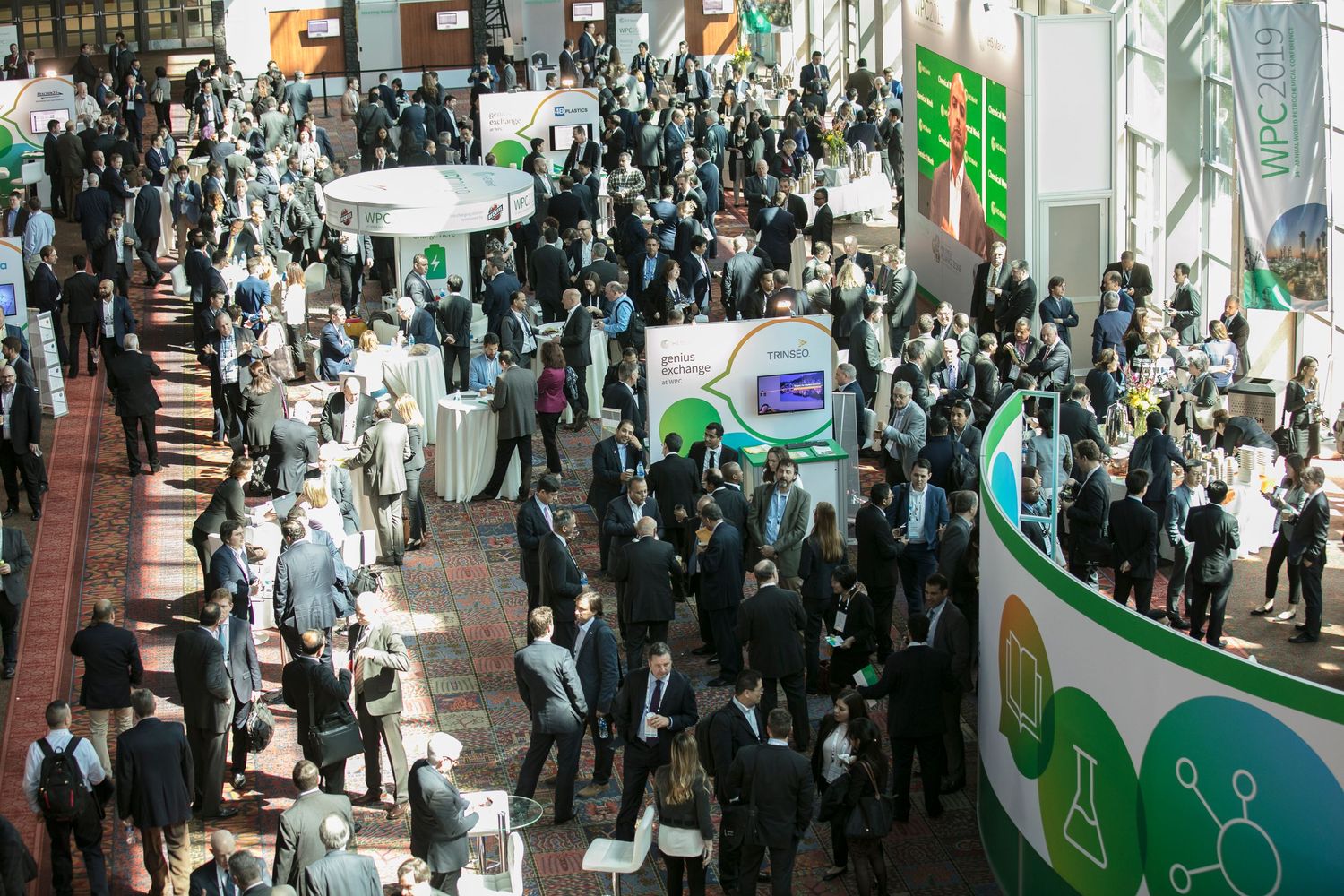 Crowded exhibition floor showing multiple rows of vendor booths and attendees networking at business event.