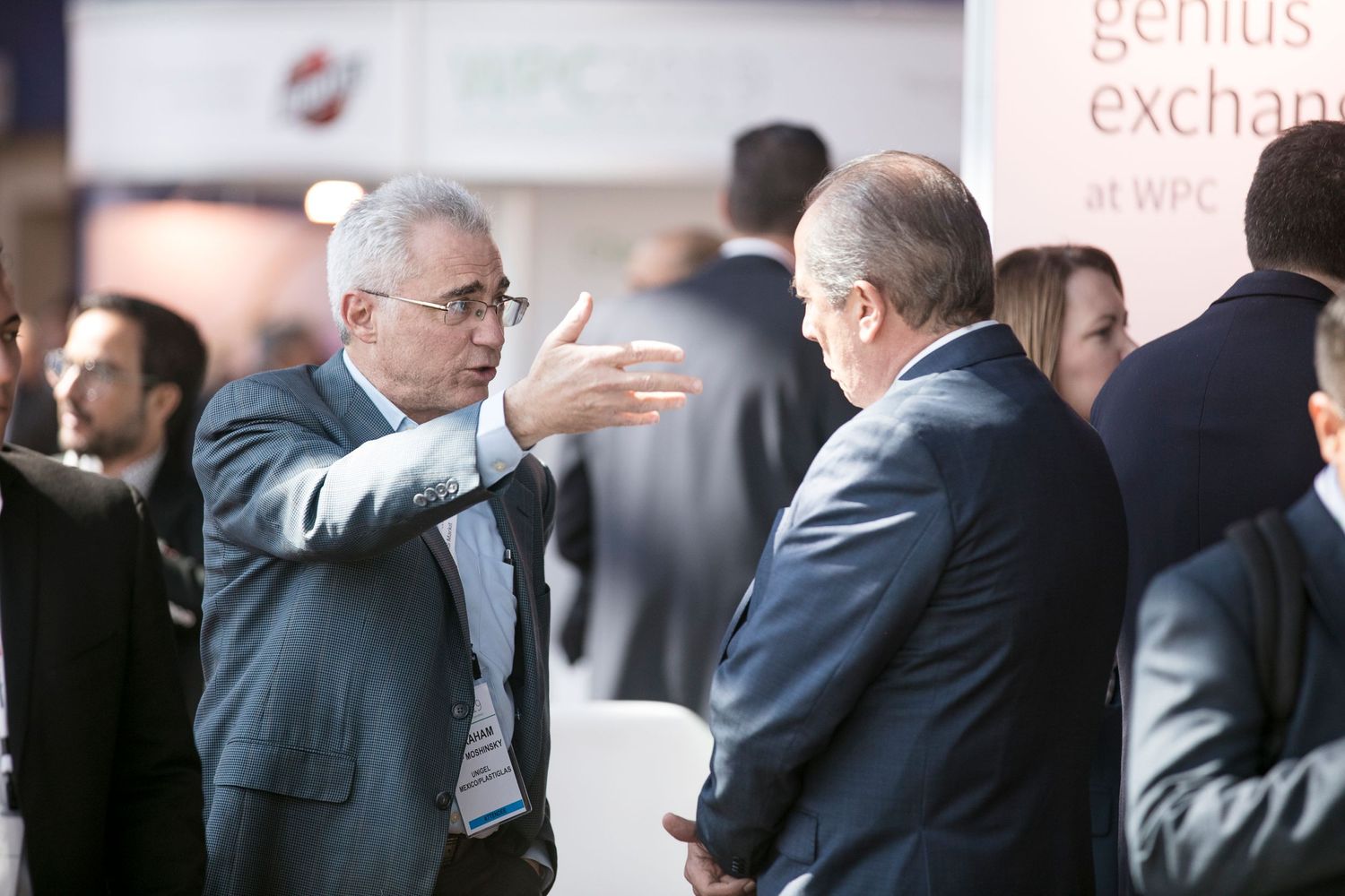 Business professionals engaged in animated discussions at networking event with bright lighting.