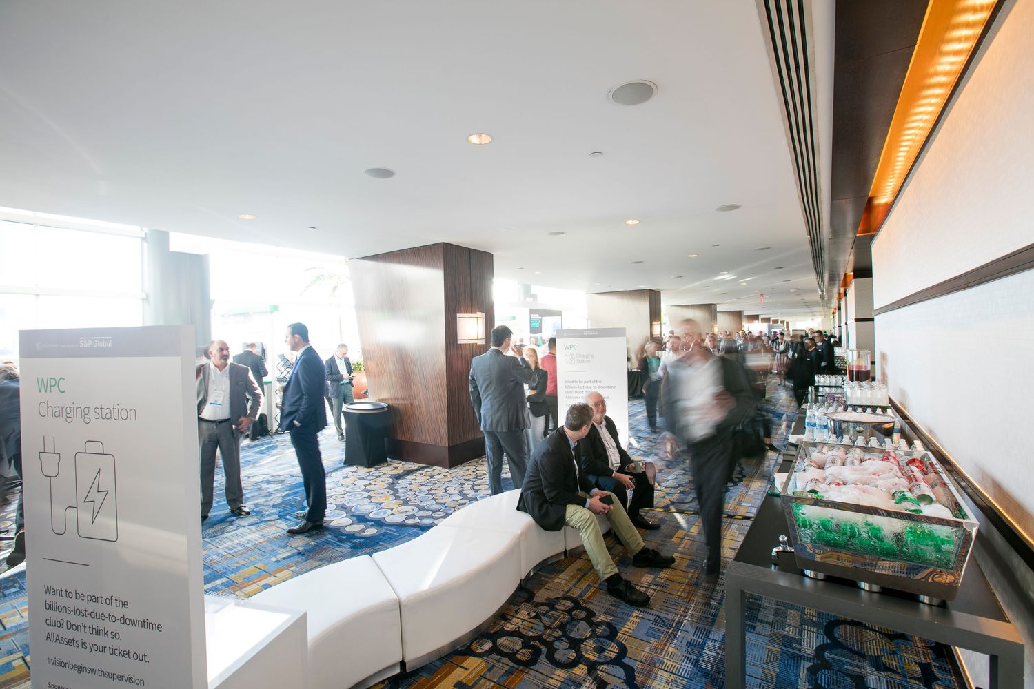 Modern conference space interior with curved walls and people gathering in small groups.