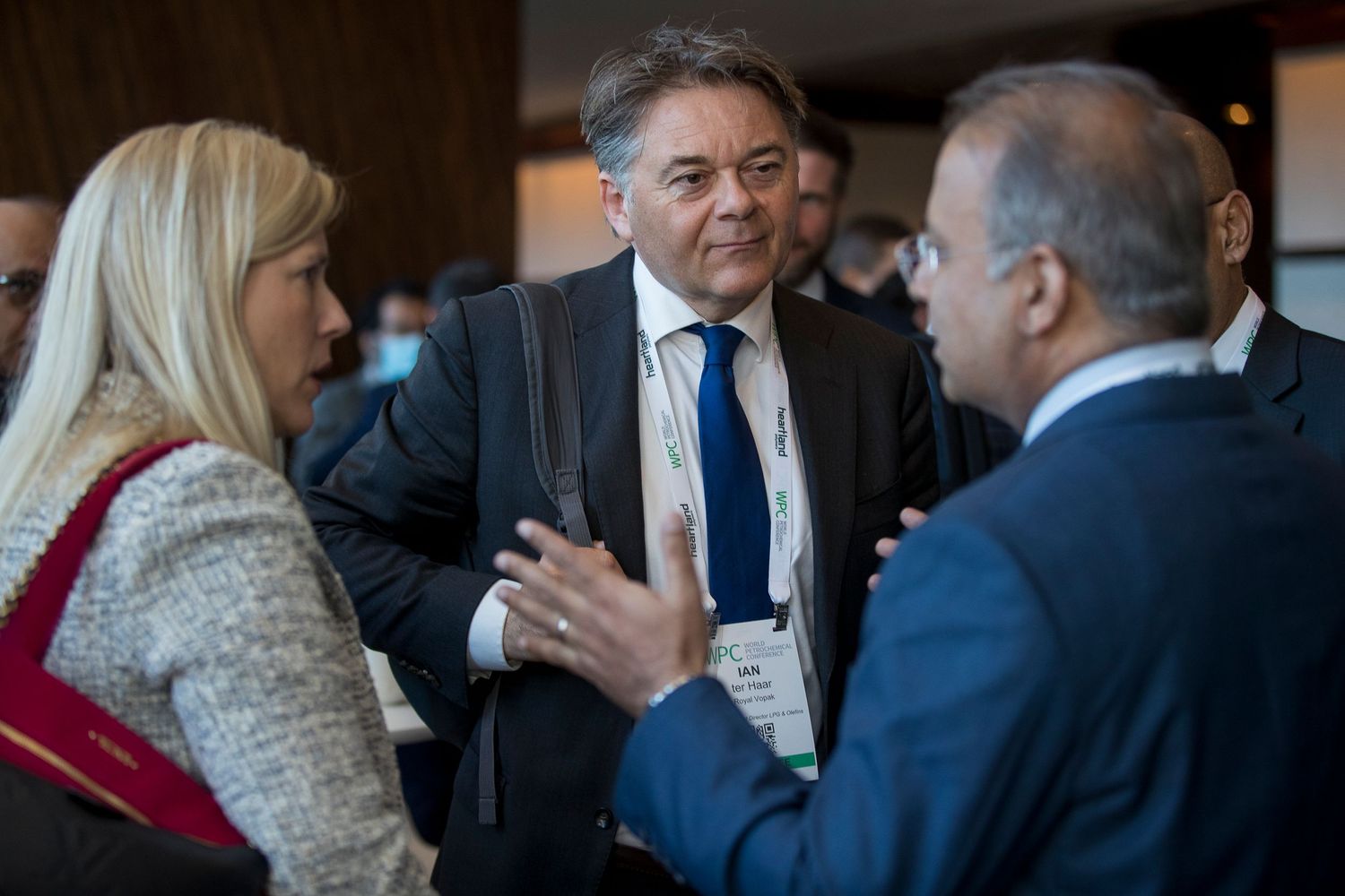 Business professionals engaged in conversation during a networking event in a dimly lit venue.