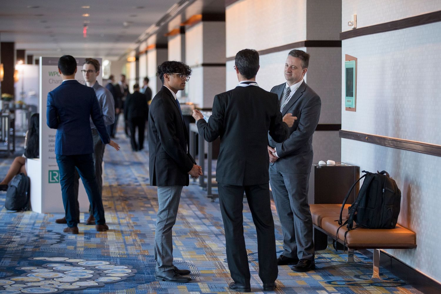 Business professionals having informal discussions in a modern office hallway.