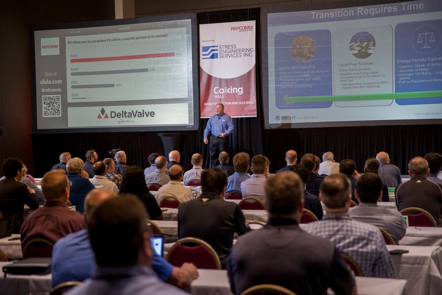 Large audience attending a business conference with presentation slides.