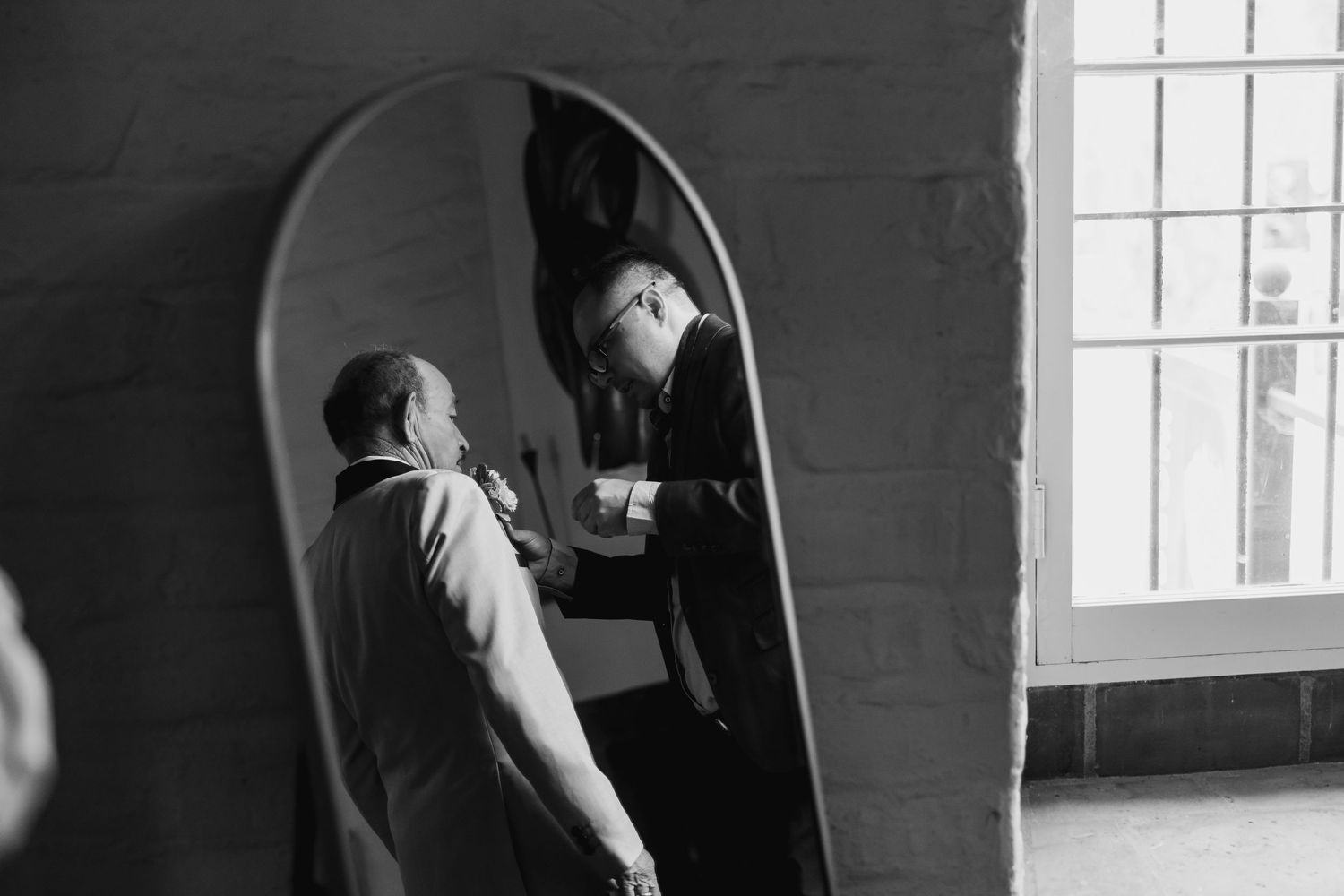 Intimate black and white portrait of couple in front of window.