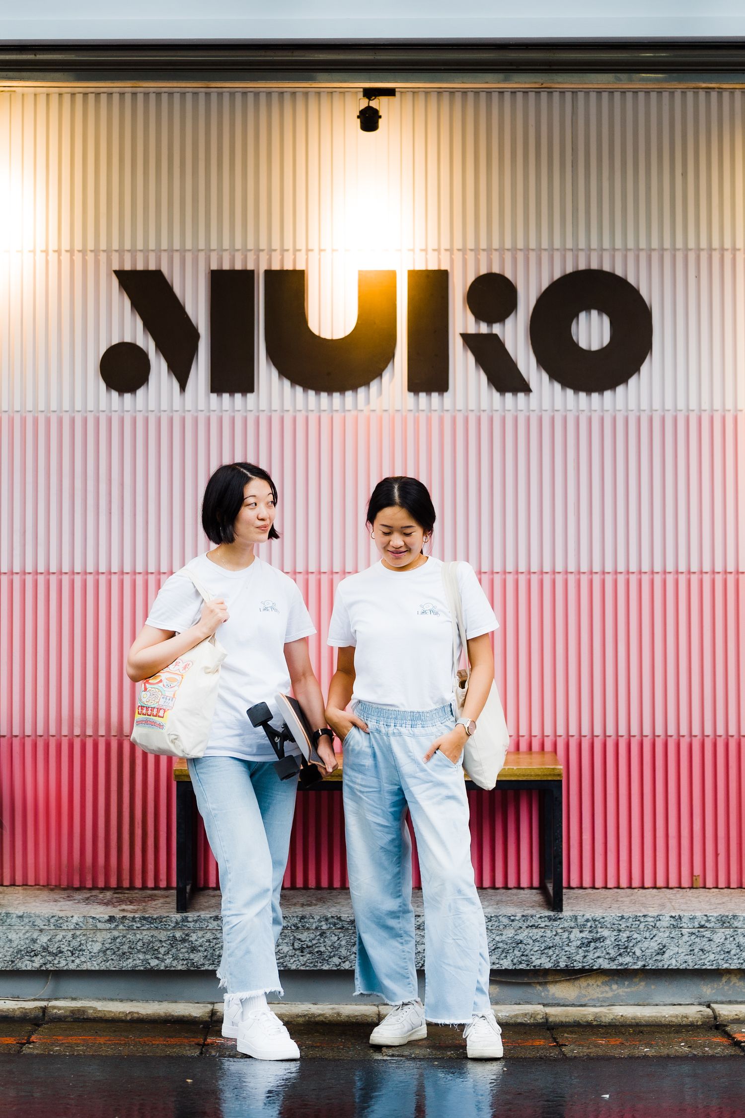 Two people in matching white shirts and jeans pose in front of MURO signage.