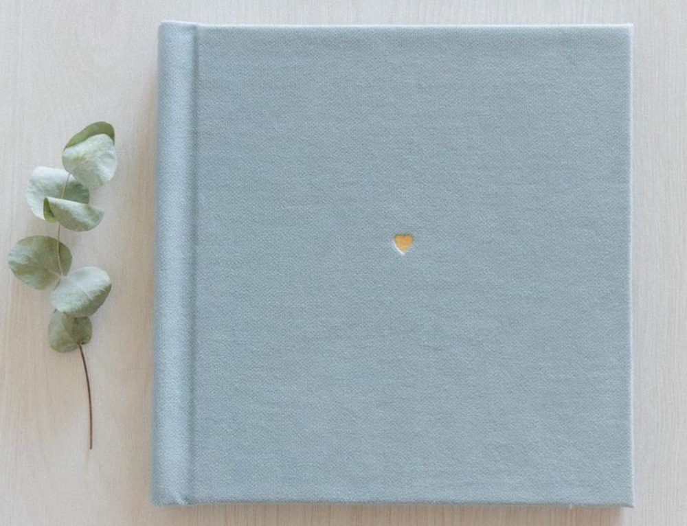 Minimalist light blue linen photo album with delicate eucalyptus decoration.