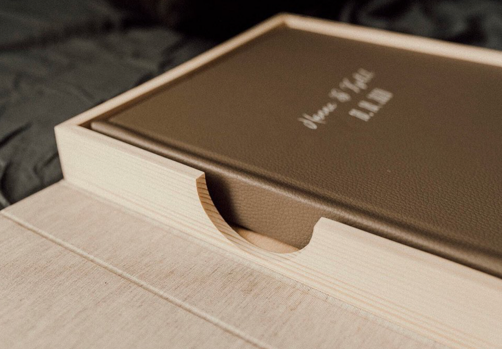 Row of elegant brown leather photo albums displayed on a light wooden surface.