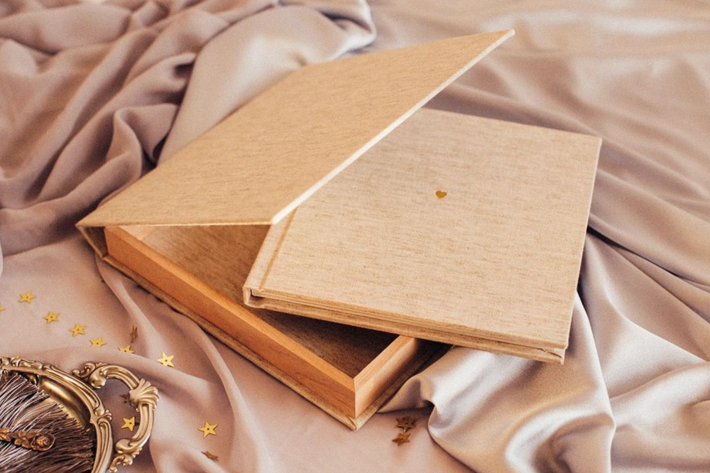 Elegant beige photo albums arranged on silk fabric.