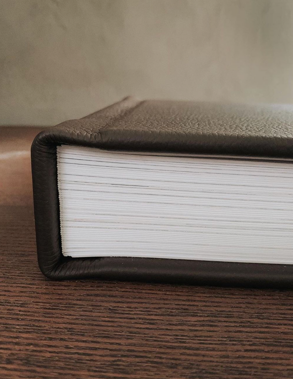 Close-up view of a leather-bound book spine on wooden surface.