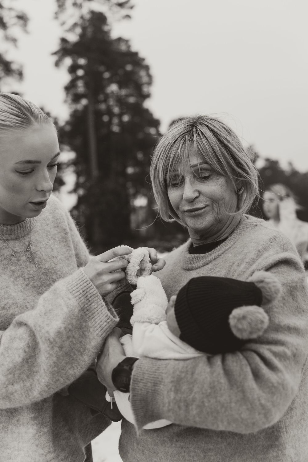 A black and white photo showing two people examining something small they're holding.
