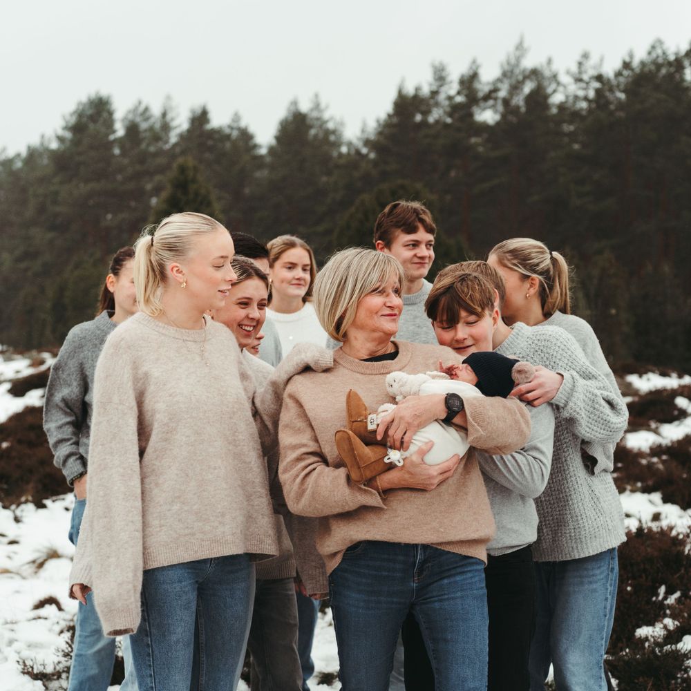 A joyful group moment outdoors as people gather around to look at something being held.
