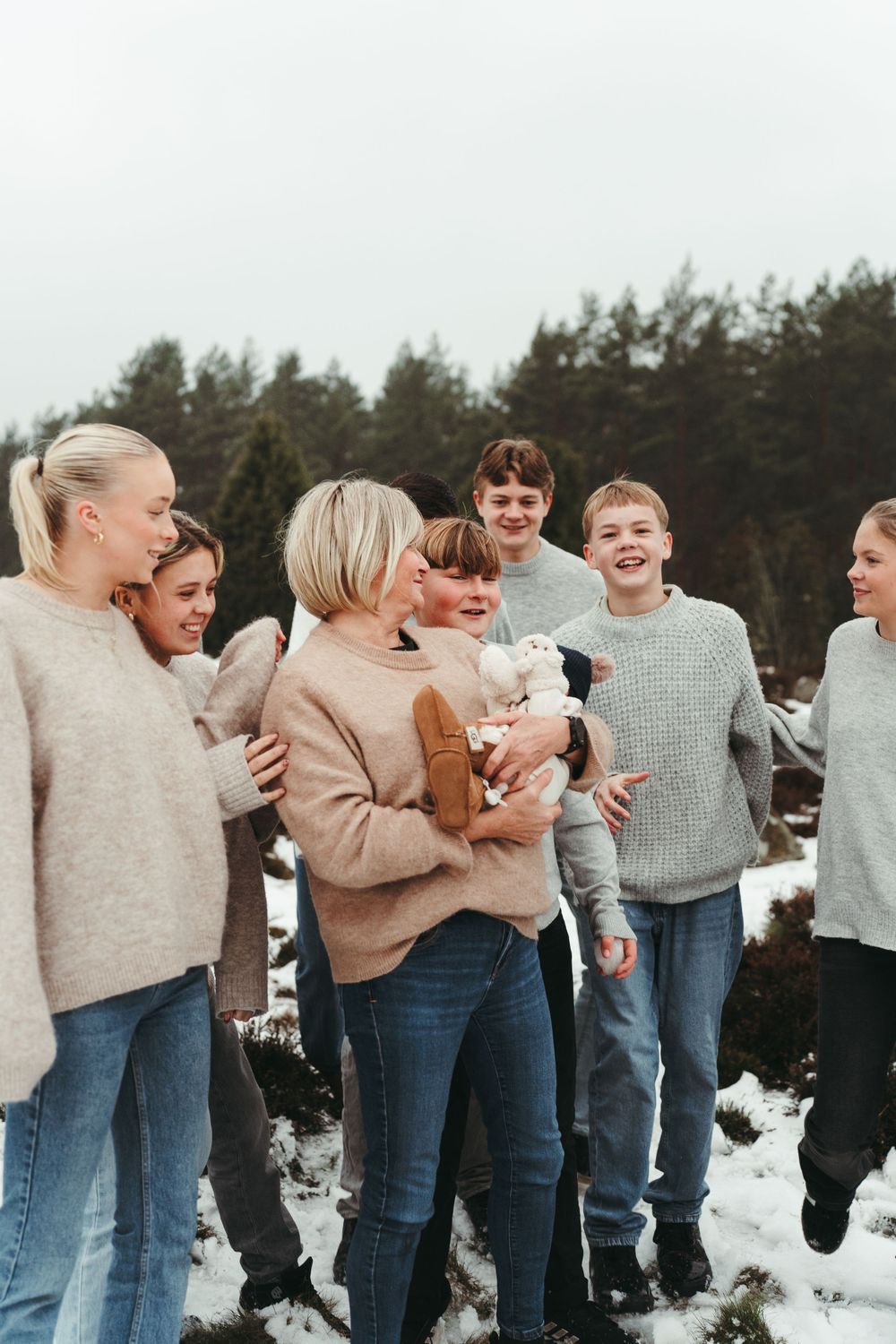 A candid winter gathering shows people in sweaters sharing laughs in the snow.