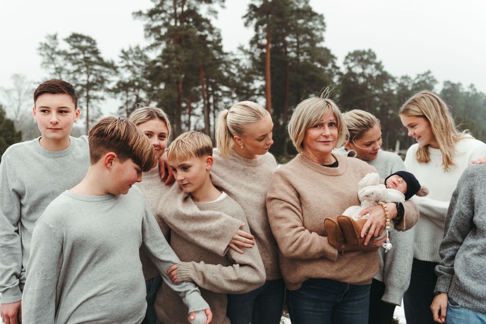A group gathers in winter wearing coordinated sweaters while someone holds a small pet.