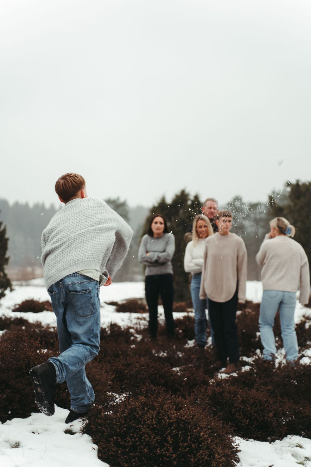 People gathered on a snowy hill during winter, wearing cozy sweaters and casual attire.