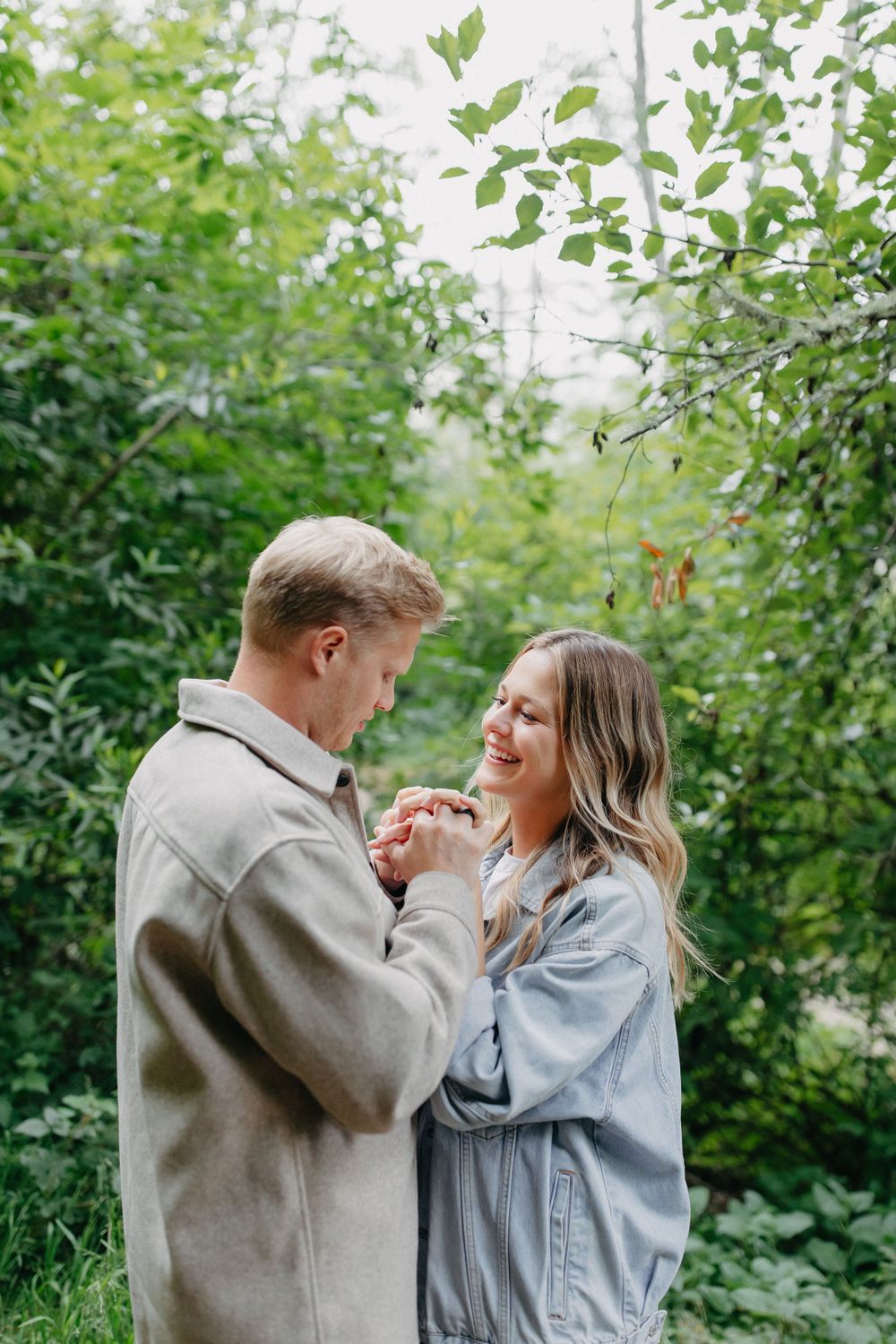 A joyful moment shared between a couple wearing casual outfits in a natural setting.