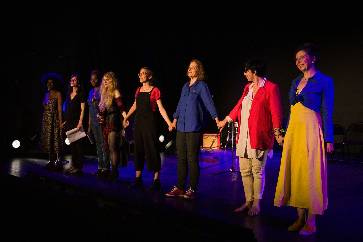 Une troupe de théâtre s'incline définitivement sur scène sous un éclairage spectaculaire.
