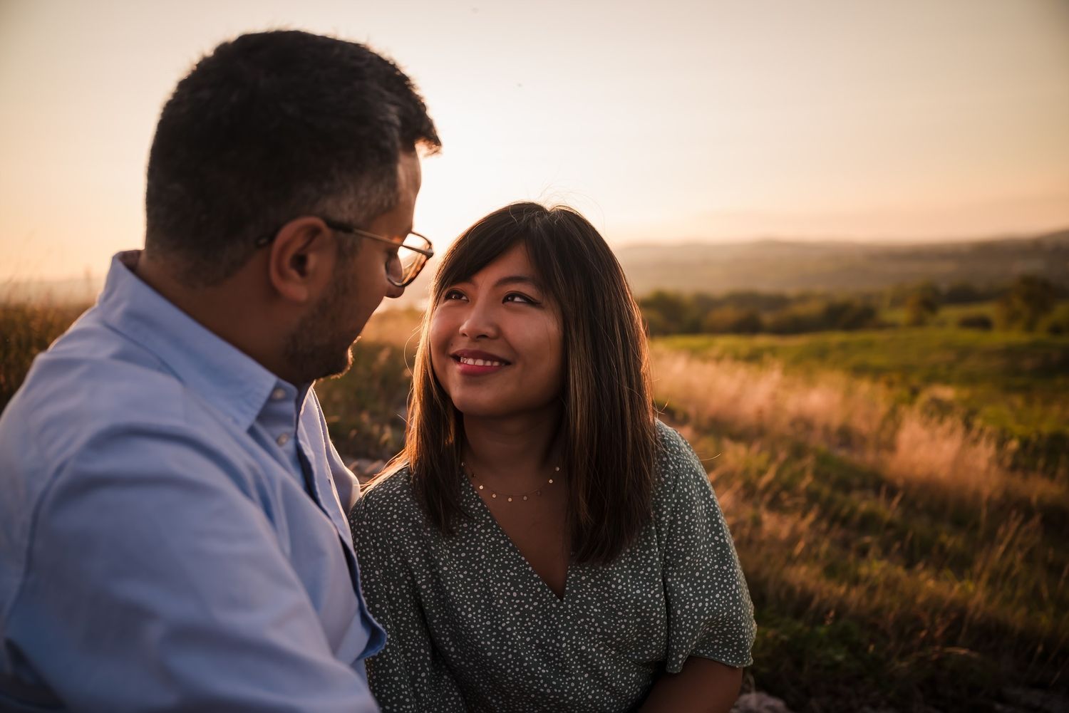 A romantic couple shares an intimate moment at sunset in a golden field.