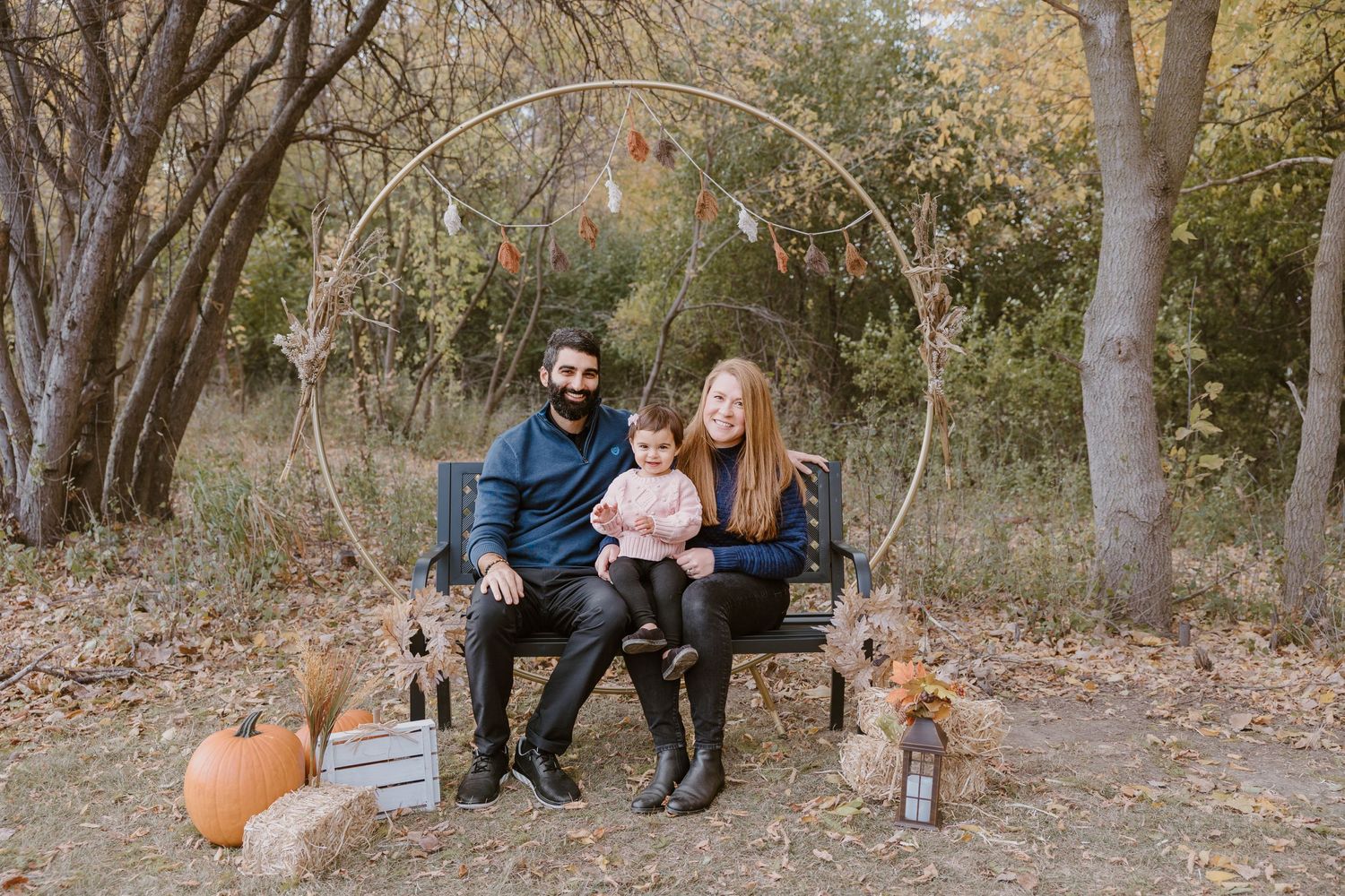Outdoor family scene on wooden swing with pumpkins and autumn decor.