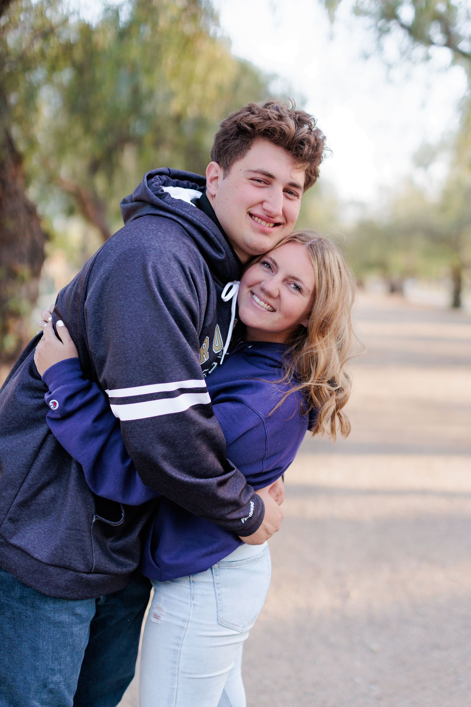 Guy and Girl Senior Photo pose where guy grabs girls and squeezer her tightly.