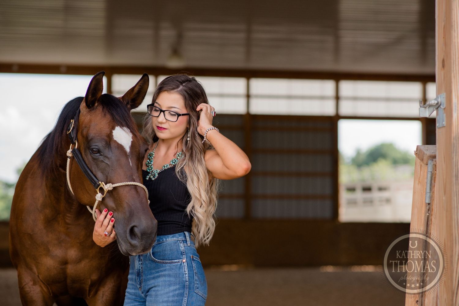 A sweet moment captured between a brown horse and its handler in a barn setting.