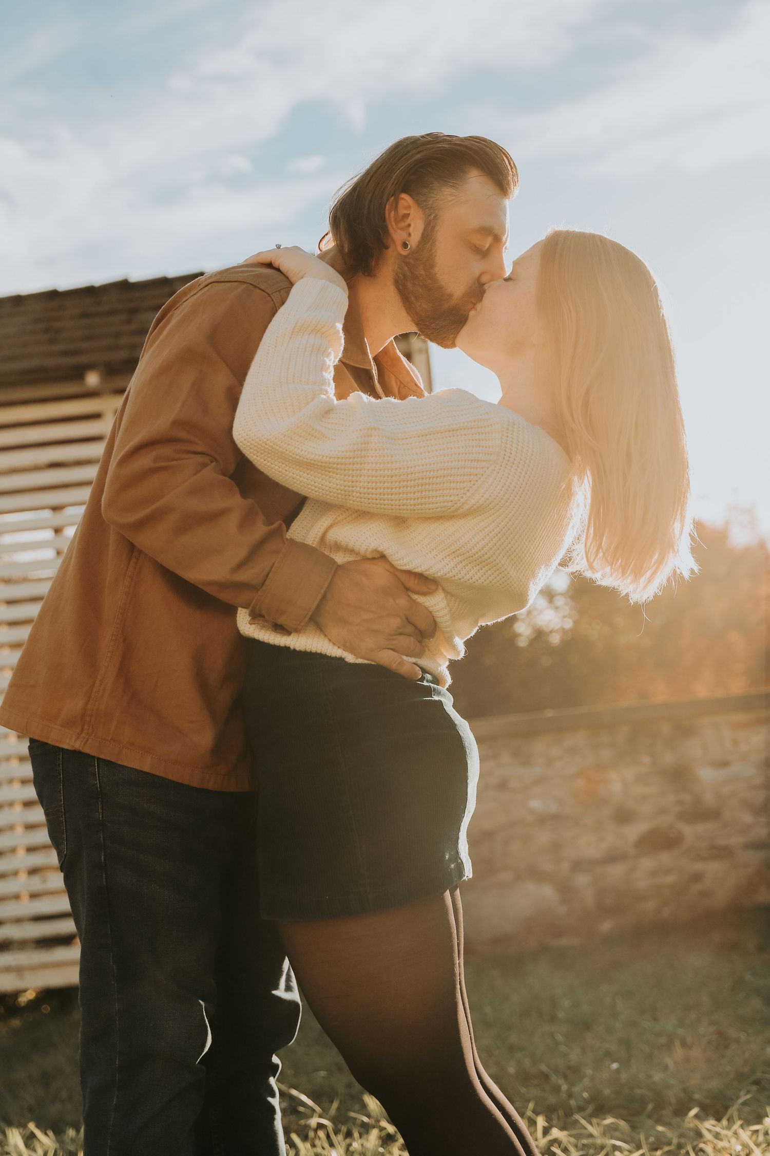 Romantic sunset embrace between couple with golden backlight.