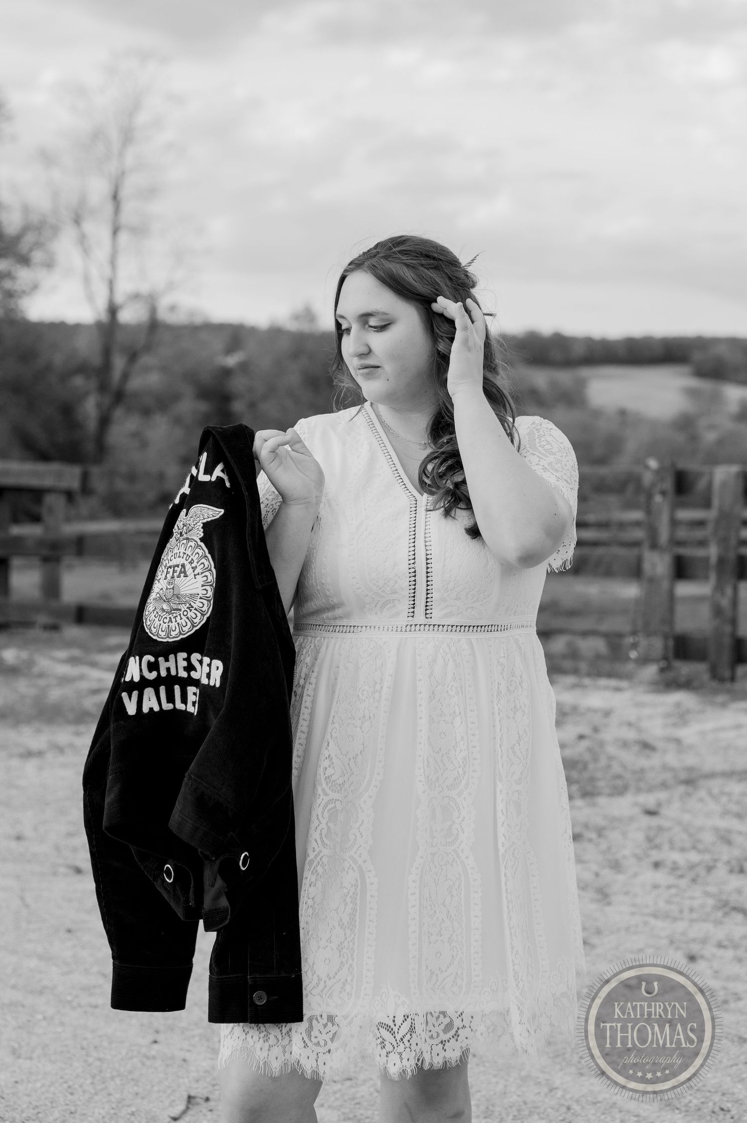 A black and white portrait of someone in a white lace dress holding an FFA jacket.