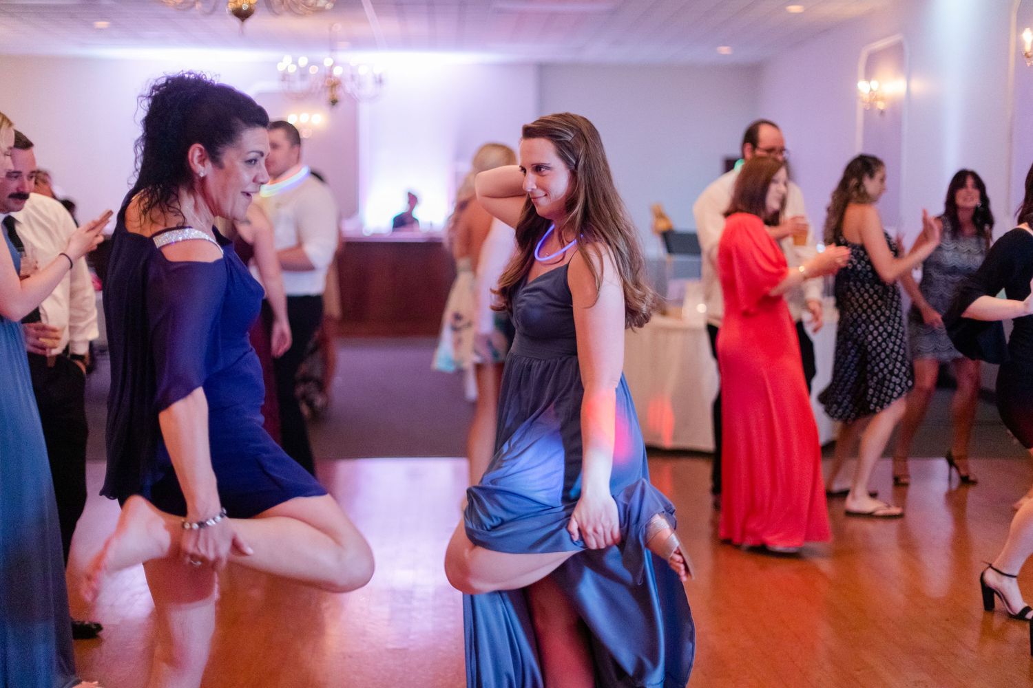 Wedding reception guests dancing and celebrating on a lively dance floor with colorful lighting.
