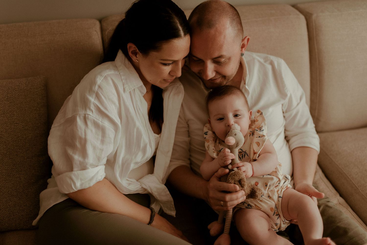 Tender family moment captured in warm tones on a cozy couch.