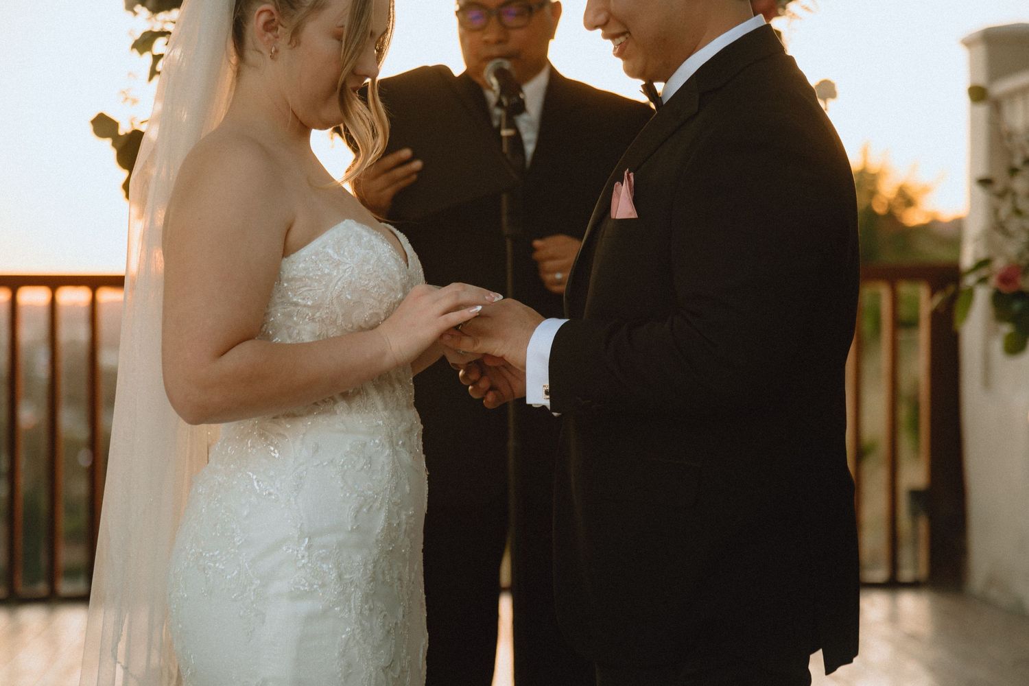 Ring exchange ceremony during outdoor wedding with officiant at sunset.