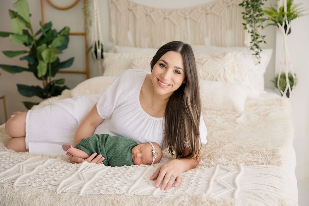 Family members relaxing together on white bedding with bohemian decor and green plants in background.