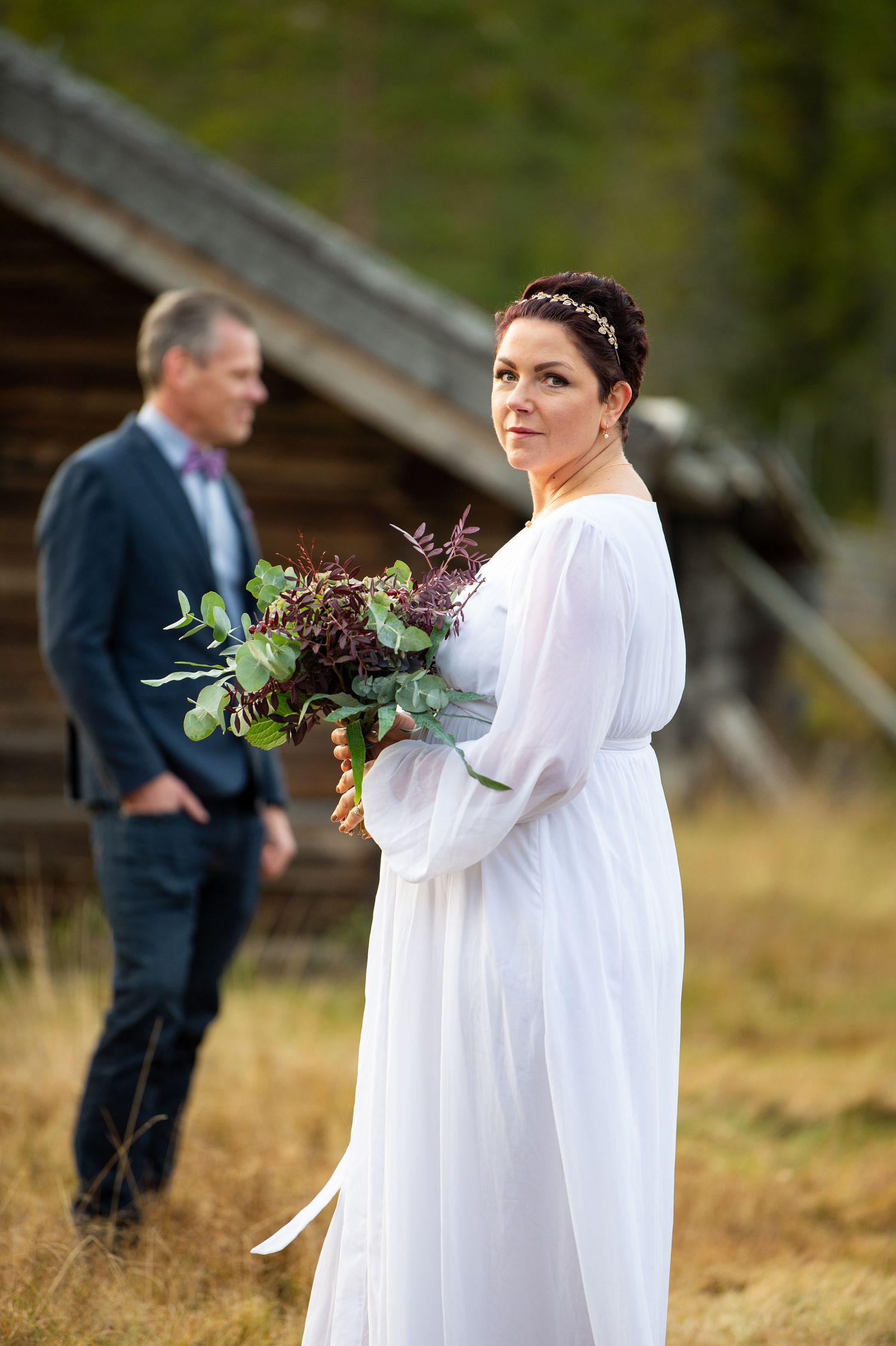 Brud i förgrunden med brudgud i suddig bakgrund