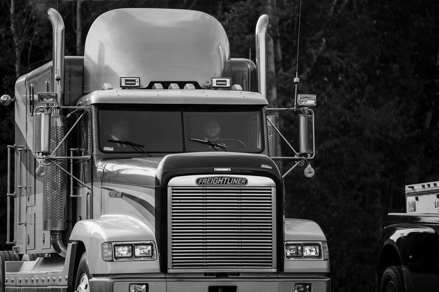 Row of semi trucks lined up at dusk creating dramatic silhouettes.