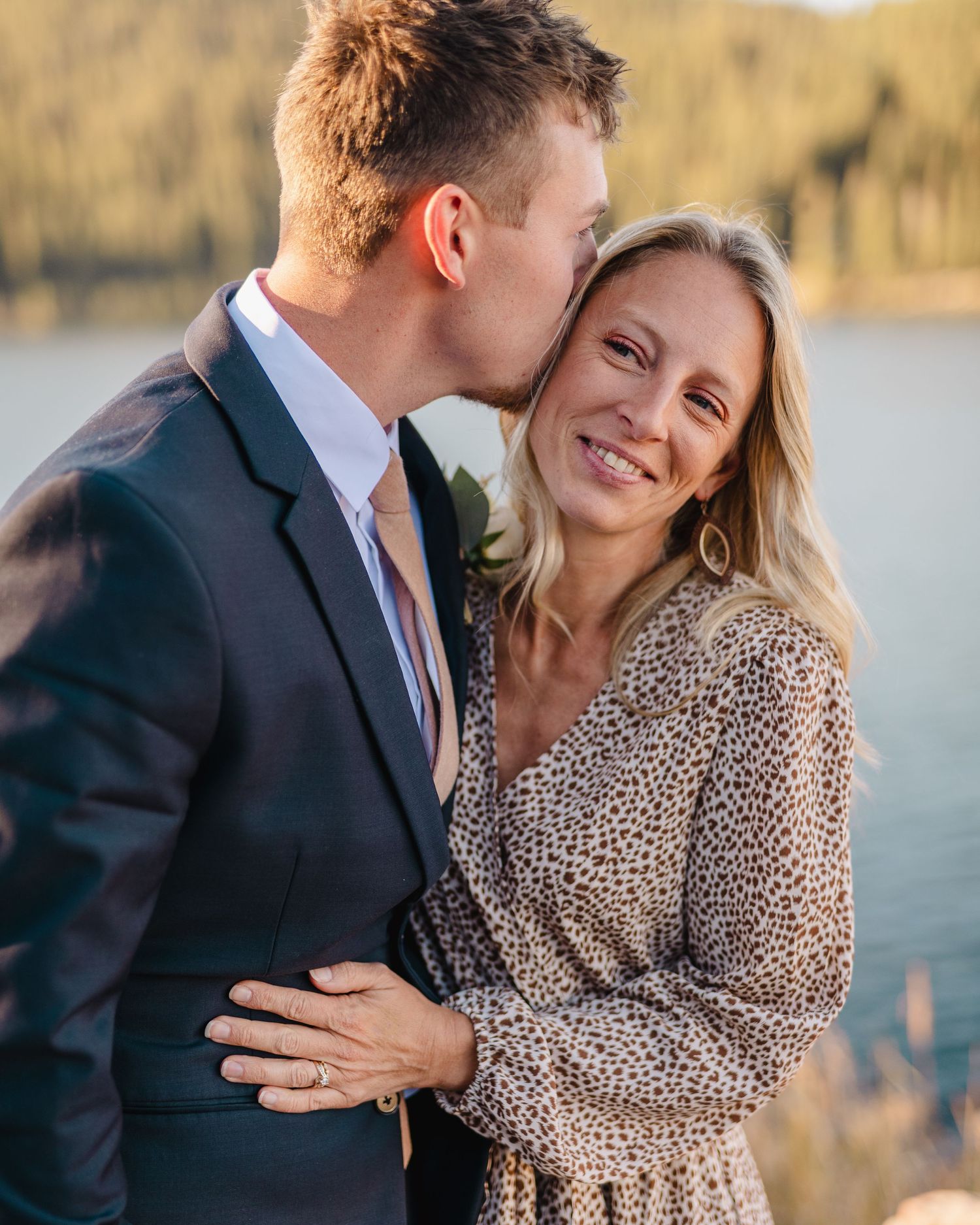 A tender moment between a couple by a lake during golden hour.